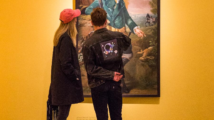 Zwei Personen betrachten ein Gemälde.