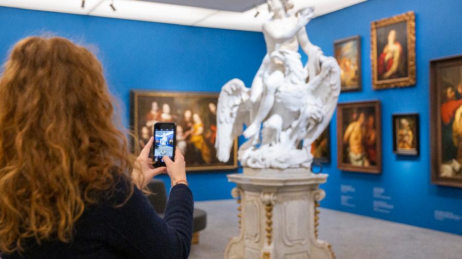 Eine Frau filmt ein Kunstwerk mit ihrem Handy.