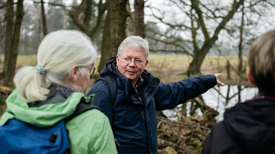 Christop Lünterbusch zeigt Teilnehmenden der Artenakademie etwas im Wald.