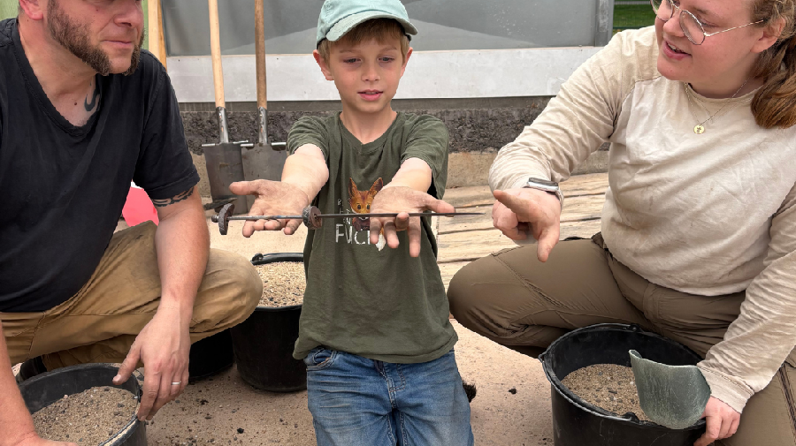 Ein Junge hat ein spannendes Objekt gefunden und die Expert:innen erklären den Fund. LWL / M. Jakob
