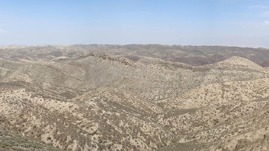 Weite, trockene Hügellandschaft unter hellem Himmel.
