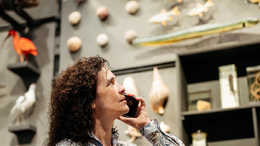 Eine Frau steht in der Gene-Ausstellung und telefoniert am Handy.