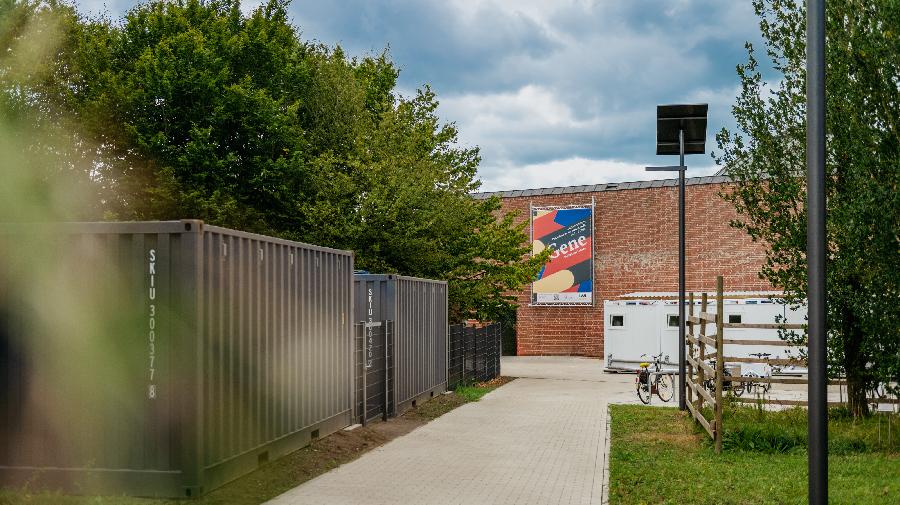 Außengelände des Museums: Blick auf das Backsteingebäude mit dem Plakat Gene-Ausstellung