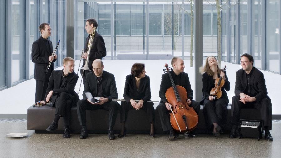 Das Ensemble sitzt mit ihren Instrument auf einer Bank 