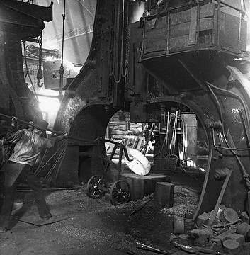 Bandagenwerkstatt: Schmieden eines Lokomotivrades: Abheben der gelochten Stahlscheibe vom Dampfhammer