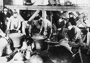 Glockengießerei: Arbeiter beim Verputzen und Nachbessern frisch gegossener Glocken