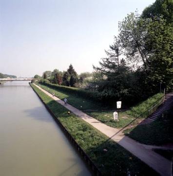 Dortmund-Ems-Kanal: Östliche Uferpromenade mit Kleingartenkolonie von der Brücke Prozessionsweg aus, im Hintergrund die Brücke Warendorfer Straße