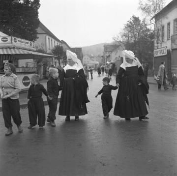 Vinzentinerinnen mit ihren Zöglingen aus dem St. Johannes-Stift Marsberg (Westfälische Klinik für Kinder- und Jugendpsychiatrie) besuchen die Allerheiligenkirmes in Marsberg, November 1955.