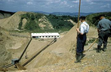 Arbeiter am Rand der Kiesgrube bei Möllenbeck mit Blick zu den Förder- und Transportanlagen in der Grube