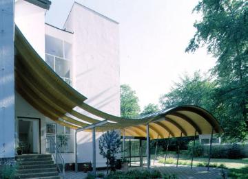 Westfälische Klinik für Psychiatrie Gütersloh, 2000: Moderne Holzüberdachung des Gebäudeeinganges Haus 26.