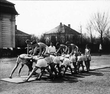 Abhärtung im Freien: Jungenklasse beim spielerischen Gruppentraining auf dem Schotterplatz