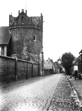 Straßenansicht mit rundem Ziegelturm der ehemaligen Stadtbefestigung