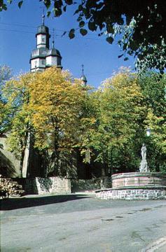 Kirchplatz mit Zierbrunnen und Kirchturm der St. Heribert-Kirche