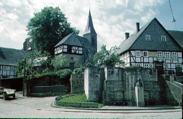 Assinghausen: Denkmal des Wilhelm Grimme (Gymnasialdirektor und Mundartdichter) mit Blick auf die St. Katharina-Kirche