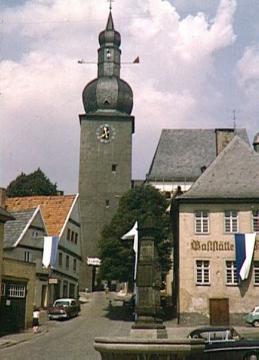 Obstadt, Alter Markt: Der Maximiliansbrunnen, errichtet 1779, mit Glockenturm der kath. Stadtkapelle St. Georg, Hallenkirche, eingeweiht 1323