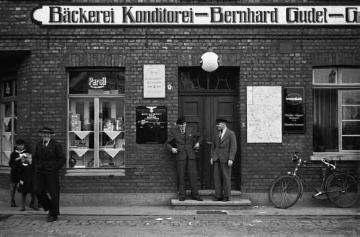 Dorfmitte mit der Gasstätte und Bäckerei Gudel mit Willi Büscher, Josef Knoop und Franz Gudel