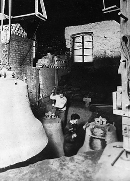 Glockengießerei: Nach dem Guß: Abschlagen der Glockengußform mit Hammer und Meißel