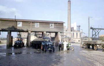 Zuckerrübenfabrik Lage: Traktoren mit beladenen Anhängern vor dem Werksgebäude