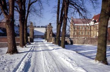Haus Hülshoff: Verschneite Zufahrt zur Vorburg mit Torpfeilern der Zugbrücke