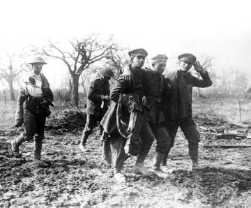 Infanterie im Ersten Weltkrieg: Britische Kriegsgefangene stützen einen verletzten deutschen Soldaten, Saint-Quentin (Frankreich) 1918