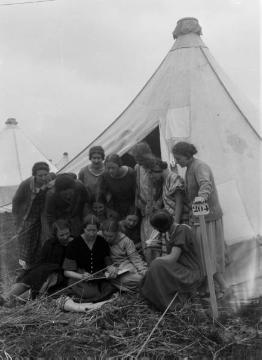 Richard Schirrmann, Familie: Singekreis mit Ehefrau Elisabeth Schirrmann (sitzend, helles Kleid) in einem Zeltlager an der See, undatiert, um 1930?