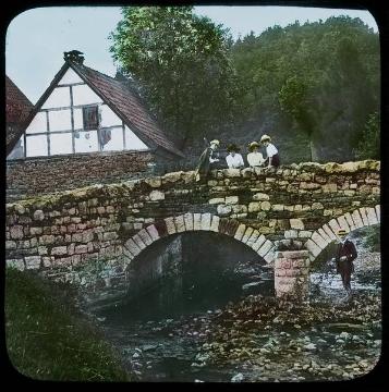 Ausflügler an der Hönne-Brücke in Balve-Volkringhausen. Links: Alte Schmiede und (angeschnitten) Wohnhaus Mühling. Undatiert, um 1912? (Ausschnittsvergrößerung von 07_1031)