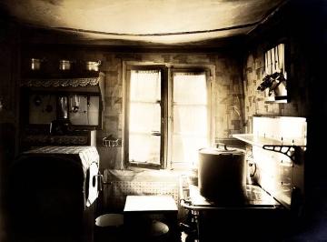 Durchhängende Decke in einem Küchenraum mit Herdstelle und Waschmaschine (inks), undatiert, 1920er Jahre - Ort und Fotograf nicht überliefert, zugeschrieben Ernst Krahn