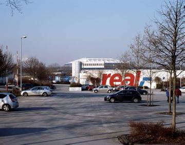 Einzelhandel in Gelsenkirchen: Supermarkt "real" der Handelskette METRO im Gewerbepark Schalke, Emscherstraße - im Hintergrund: das Fußballstadion "Veltins-Arena", bis 2005 "Arena Auf Schalke"