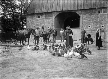 Hofwirtschaft: Bäuerin bei der Hühnerfütterung, um 1910