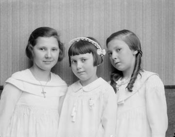 Kommunionkind Irene Jäger (*um 1928) porträtiert um 1936 mit ihren Schwestern Margret (links) und Agnes - Töchter des Fotografen Ernst Jäger und Ehefrau Agnes. Atelier Jäger, Harsewinkel, undatiert.