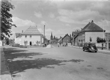 Harsewinkel um 1955: Gütersloher Straße Richtung Dorfmitte mit Blick auf St. Lucia-Kirche, links geht die Neustraße (seit 1957: August-Claas-Straße) ab, Metzgerei Heinrich Paul und rechts Haus Wewer.