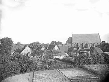 Dorfkern Harsewinkel: St. Lucia-Kirche (eingeweiht 1860, späterer Turmbau 1903/1904) und Häuser am Kirchplatz (Gartenseite), aufgenommen vom St. Lucia-Hospital. Undatiert, um 1900?