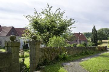Dorfzentrum Borgeln: Kirchmauer des Pfarrhofs an der ev. Dorfkirche mit Blick auf Wohnhäuser an der Diedrich-Düllmann-Straße. Juni 2016.