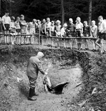 Schulklasse mit dem Archäologen Otto Krasa an der Fundstätte eines keltischen Eisenschmelzofens ("Rennofen", 500 v. Chr.)