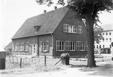 Harsewinkel, Münsterstraße [etwa Haus-Nr. 31/33]: Hauptverwaltung der Claas Landmaschinenfabrik (rechts). Vorn: unbezeichnetes Gebäude, später abgebrochen zugunsten eines Parkplatzes. Undatiert, um 1950?