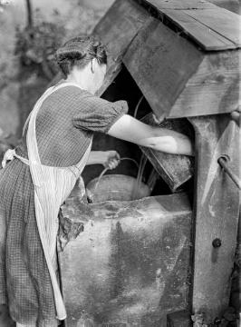 Bäuerliche Hauswirtschaft: Bäuerin beim Wasserholen am Ziehbrunnen. Vermutlich Ostwestfalen. Ohne Angaben, undatiert, um 1940?