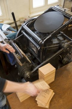 Herstellung von Zigarrenkisten: Die Kistendeckel werden an einer Tiegeldruckmaschine bedruckt. Fertigungsdokumentation in der Cigarrenfabrik August Schuster, Bünde, 2015