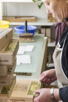 Herstellung von Zigarrenkisten: Herkunfts- und Qualitätssiegel werden aufgebracht. Fertigungsdokumentation in der Cigarrenfabrik August Schuster, Bünde, 2015.