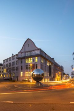 Herford, Goebenstraße mit Elsbachhaus, 2015 - ehemals Hemdenfabrik Elsbach, erbaut im Jugendstil 1909, heute Bürohaus und Einkaufszentrum. Auf der Verkehrsinsel: "La Palla" (Der Ball), Skulptur von Luciano Fabro. Ansicht im März 2015.