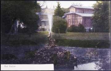 Bad Hamm, Sole-Kurbad 1882-1955: Springbrunnen im Kurpark mit Blick auf das Badehaus (rechts) von Norden. Postkarte, undatiert, um 1905 [?]