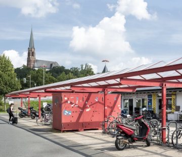 Innenstadt Fröndenberg: Fahrradparkplatz am Bahnhof, Wilhelm-Feuerhake-Straße Höhe Harthaer Straße. Im Hintergrund: Kath. St. Marienkirche (Auf dem Sodenkamp). August 2017.