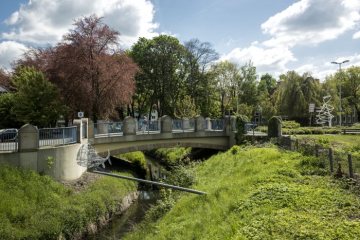 Sesekepark Kamen Höhe Partnerschaftsbrücke, Mail 2017. Vorn: Fischskulptur "Der Kömsche Bleier" (Lothar Kampmann), rechts: Kreisel Sesekedamm mit Stahlrohrskulptur „Drei Säulen“ (Manfred Jockheck, 2009). Mai 2017.