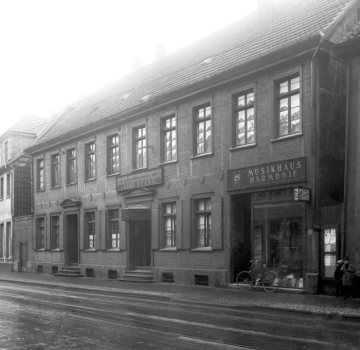 Musikhaus Harmonie, Hamm, Ostraße 52 - Inhaber B. Schierbrock. Links: Kornbranntwein-Brennerei und Schankwirtschaft Carl Oberg, Oststraße 54. Undatiert, 1930er oder 1940er Jahre.