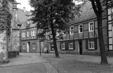 Delbrück-Kirchplatz um 1952: Fachwerkhäuser im Kirchenrundling an der St. Johannes Baptist-Kirche (Ostseite). Angeschnitten rechts: Älteste Schule der Stadt, später Haus Otto Pache.