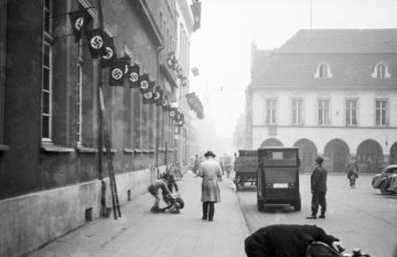 Marktplatz Hamm aus Richtung Widumstraße. Links: Gebäude der Klub-Gesellschaft ("Hitler-Platz" 5) mit Hakenkreuzbeflaggung. Rechts: altes Rathaus (bis 1927) und Kleine Weststraße. Undatiert, um 1936 [vgl. Bild-Nr. 17_1793 vom gleichen Tag].