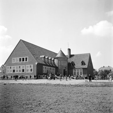 Schüler auf dem Pausenhof vor dem neuen Schulgebäude mit altem Turm