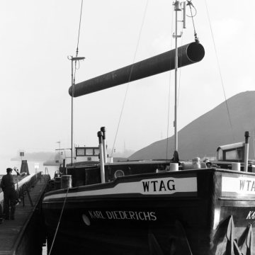 Verladung von Stahlröhren eines Röhrenwerks in Herne [Firmenname unbekannt] auf ein Frachtschiff am Rhein-Herne-Kanal. Februar 1977.