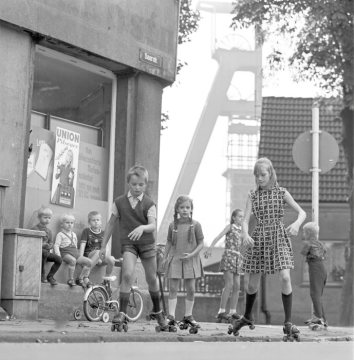 Spielende Kinder auf Rollschuhen in der Saarstraße, Herne-Sodingen, um 1968. Im Hintergrund der Förderturm von Zeche Mont Cenis.