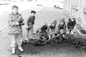 Nach Abkippen der Kohlelieferung vor der Haustür: Kinder beim Beseitigen der Brikettreste vom Gehsteig. Castrop-Rauxel, März 1978.