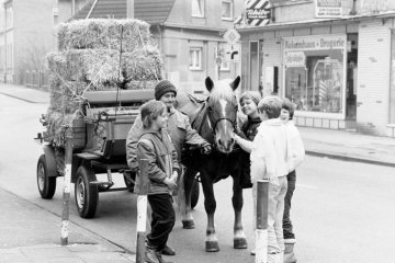 Gruppe von Kindern mit einer älteren Frau mit Pferdefuhrwerk, mit Stroh beladen, Bochum, im April 1986.